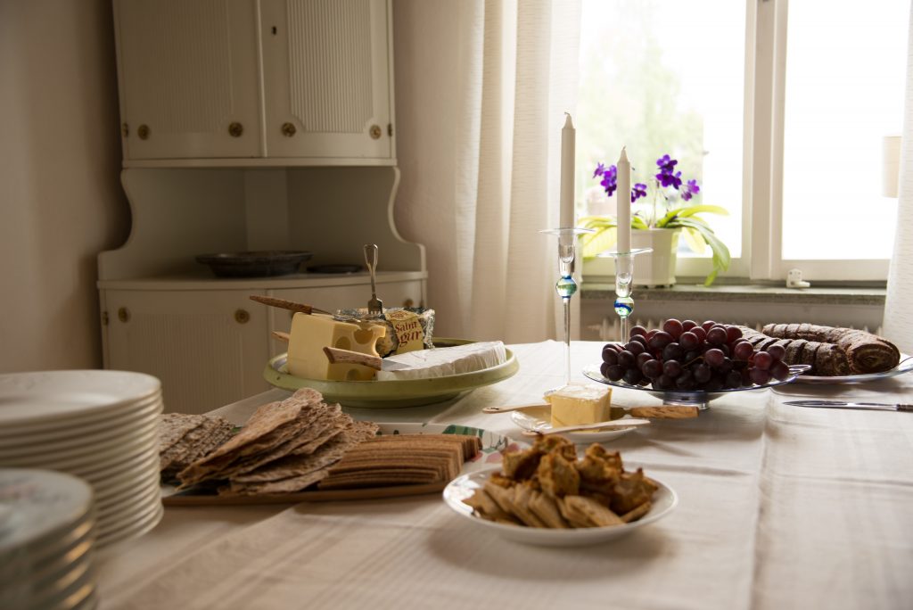 Un table dressée avec du fromage, des assiettes et du raisin
